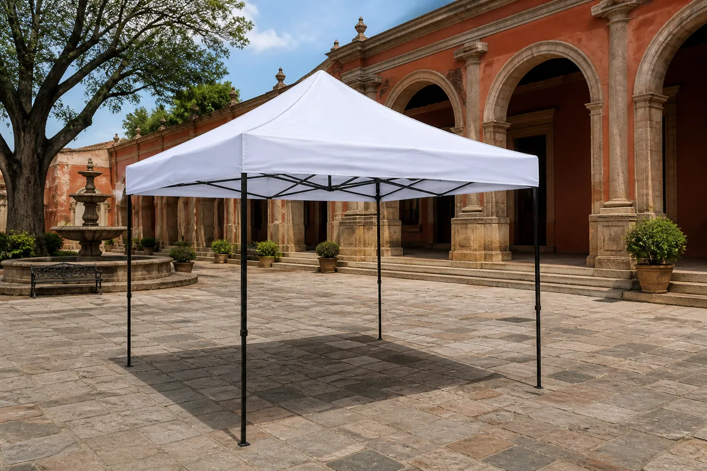White square pop-up canopy on a colonial plaza of stone pavers, with a fountain and terracotta arched arcade behind it.